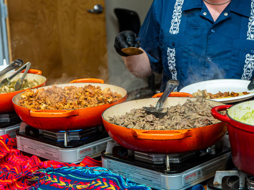 A Cazuelita's team member serving food from buffet pans